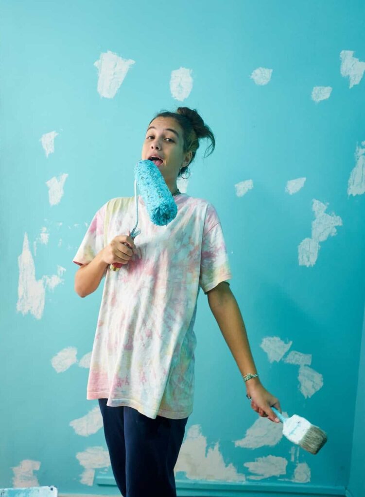 happy woman painting interior wall with paint roller